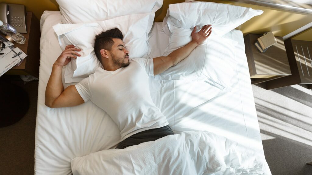 Young man sleeping in bed, staying in hotel
